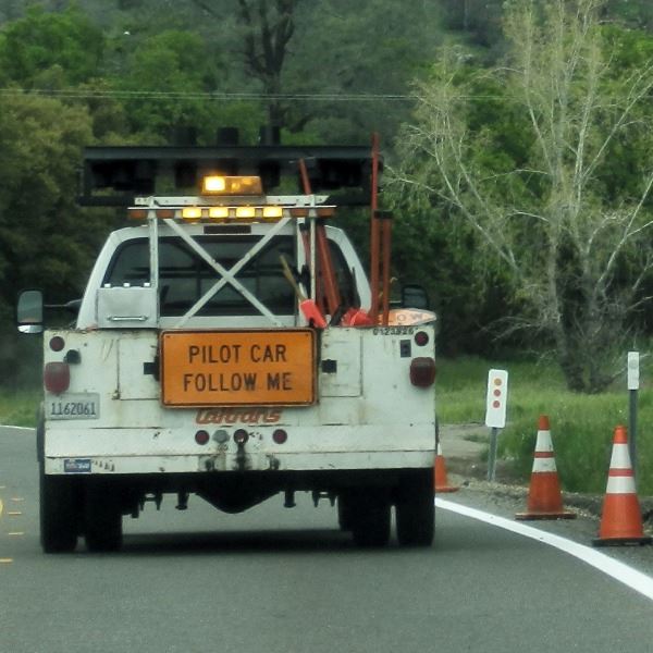Back of a white truck driving down the street with sign that says 