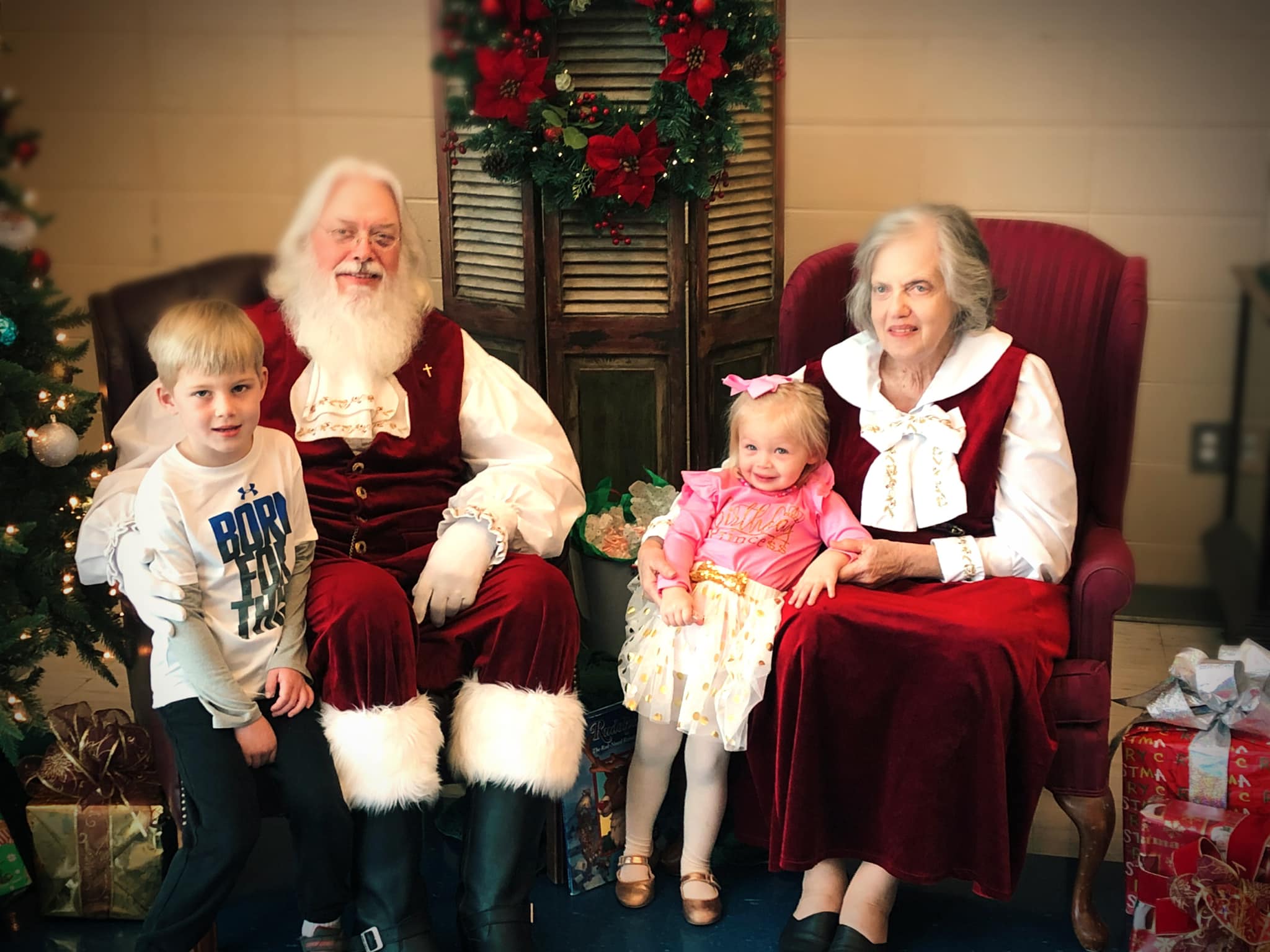 Mr. and Mrs. Santa with two small children in their lap. 